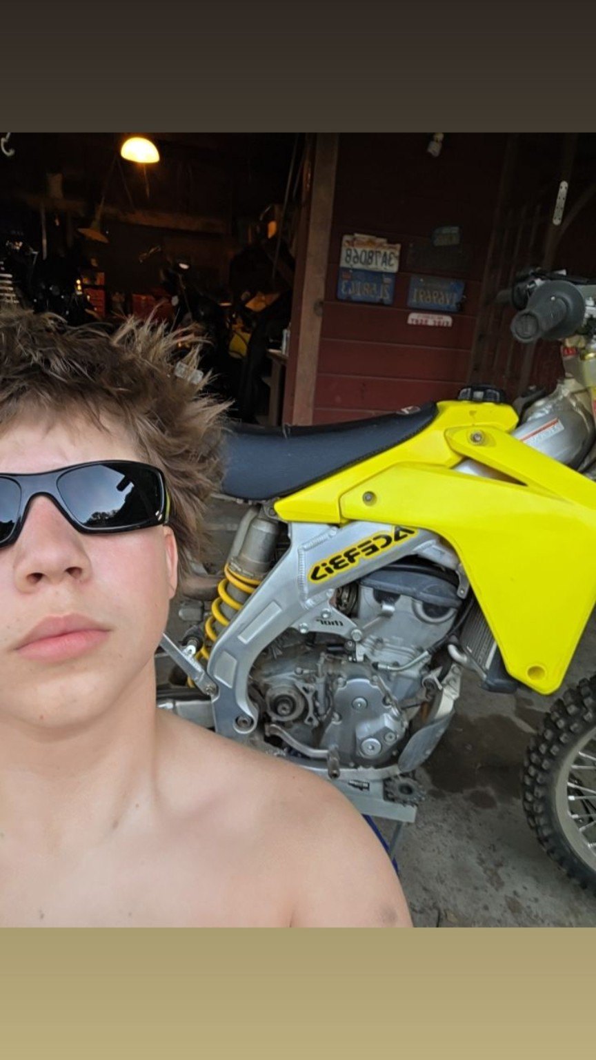 Carter wearing sunglasses beside his yellow dirt bike